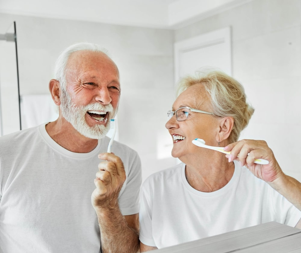 Couple âgé se brossant les dents en souriant